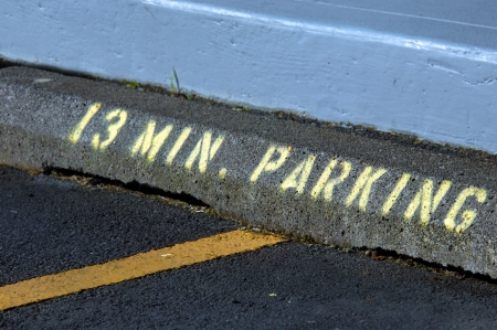 Random time limits parking to 13 minutes   Concrete curb has stenciled lettering and numbers in yellow spray paint の写真素材