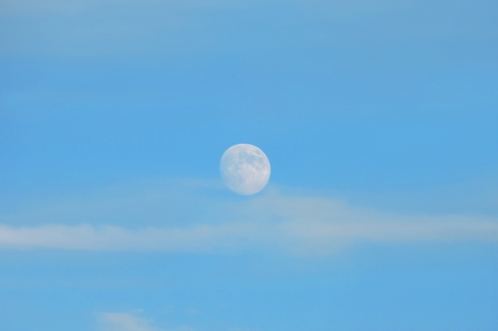 Background image of a full moon reflected in the daylight sky   の写真素材