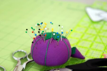Purple pin cushion is stuck with colorful pins   Background image has room for personalization の写真素材