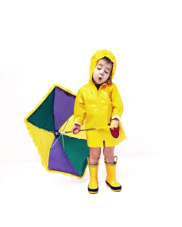 Little girl is wearing a yellow raincoat and boots.  Her umbrella is open and she is speaking.の写真素材