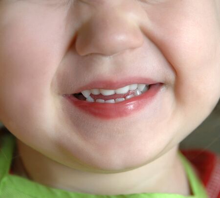Image shows extreme closeup of a little girl who is smiling and happy.  Photo shows chin, mouth and...