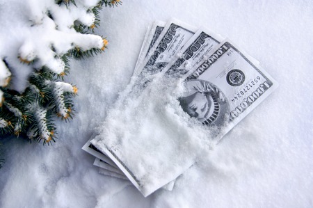 Pile of play money is covered with snow.  Fir branches frame stash of money.の写真素材