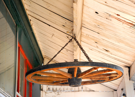 Old, wood wagon wheel is recycled and used as decoration.  It is hanging in the eaves of an old house in Wyoming.の写真素材