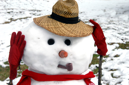 Distressed snowman holds his head with his red, gloved hands.  He is upset that winter is ending and melting away.  Water drips from his nose.の写真素材