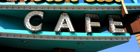 Cafe sign is turquoise with white letters.  Vintage sign is lit by multiple light bulbs.の写真素材