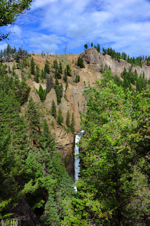 Scenic view of Tower Falls in Yellowstone National Park.  Water cascades from a steep cliff on the face of a mountain.の写真素材