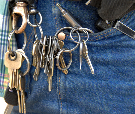 Door keys hang from many loops on a janitors key chain.  He has tools in his pocket and is ready for anything.の写真素材