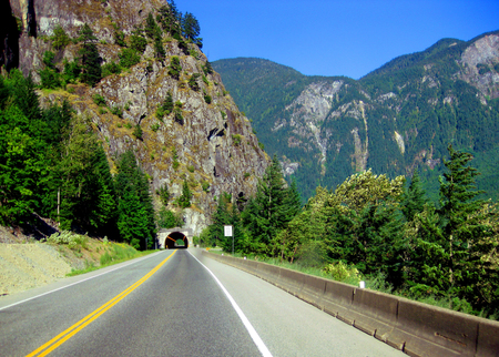 Highway tunnel approaches and passes through the rugged mountainside while driving the Alaskan Highway.の写真素材
