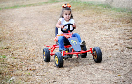 Little girl drives a go cart on a dirt track in Tennessee.  She has a determined look on her face as she gives it her all.の写真素材