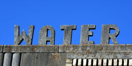 Large and old water sign would be welcome to someone stranded in the desert and desperate.  Vivid blue sky frames letters.の写真素材