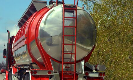 Red and silver tanker truck delivers liquid.  It is driving on a highway.の写真素材