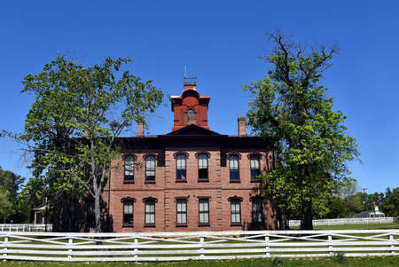 The Courthouse at Historic Washington State Park is red brick.  It is surrounded by a white, wooden fence.  Trees hug corners of building.のeditorial素材