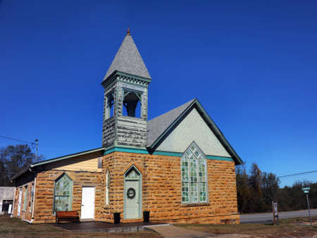 Bell tower on the Church of the Nazarene in Marshal, Arkansas has a Victorian style.  Built of stone bricks and trimmed in green paint.の写真素材