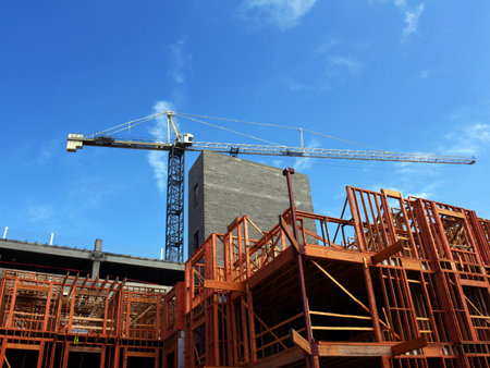Tall crane stands above a construction site in Memphis, Tennessee.  Wooden framing stands open ready...