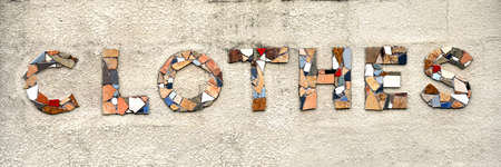 The word clothes is formed from broken tile pieces.  Letters are mounted on concrete wall.の写真素材