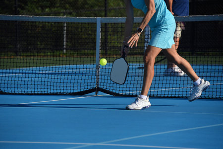 Senior female leans down to serve the ball during a pickle ball match in Asheville, North Carolina.