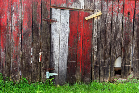 Old barn door is shut and held in place with wooden latch and rusty hinges.  Background image shows cracked, faded and weathered boards.の写真素材