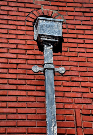 Stron City, Kansas, train depot has a vintage drain pipe and cover mounted on the exterior, red brick, wall of building.の写真素材