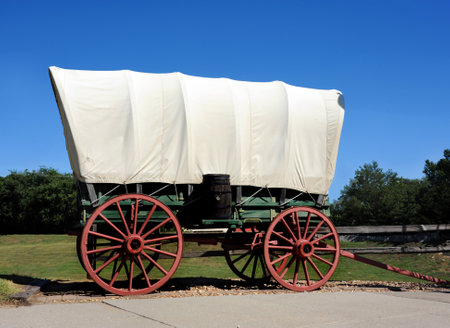Covered wagon is displayed in Council Grove, Kansas.  Wagon bed is green and wheels are red.