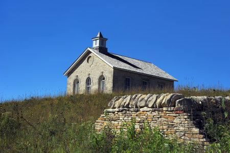 Lower Fox Creek School stands on a hill in the Tallgrass Prairie National Preserve, near Strong City, Kansas.  All that remains of the old stone wall sits in front of school.の写真素材