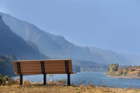 Bench sits all alone on a bluff overlooking the Columbia River Gorge and Cascade Mountainns.の写真素材