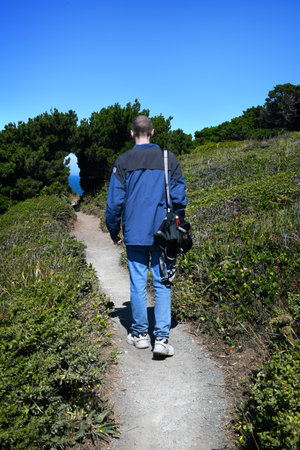 Tourist hikes the Orford Heads Trail on the coast of Oregon.  The trail goes through a tunnel of trees and disappears in the distance.の写真素材