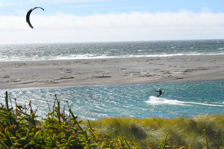 Kite Surfer hangs on as the wind takes he and his board gliding across the water on the coast of...