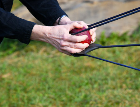 Female, wearing a black sweater, pulls back on a catapult and shoots an apple at a target.  Game...