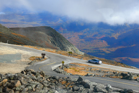 Grey compact car has completed the Mount Washington Auto Road, in New Hampshire.  Autumn has colored the mountains.の写真素材
