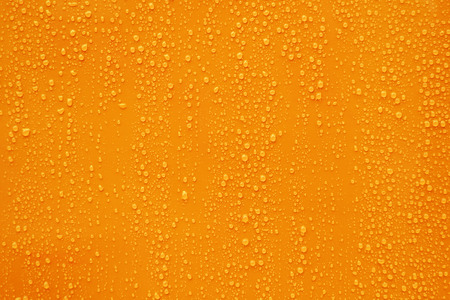 Close up water drop on dark orange background.の写真素材