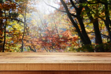 Wooden table and blur autumn background.