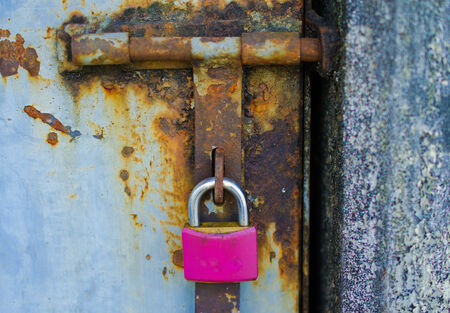 A pink padlock on a rusty blue gageの写真素材