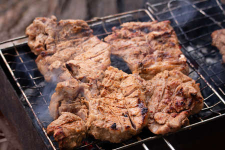 Beef steak on grill. Meat on coals with smokeの写真素材