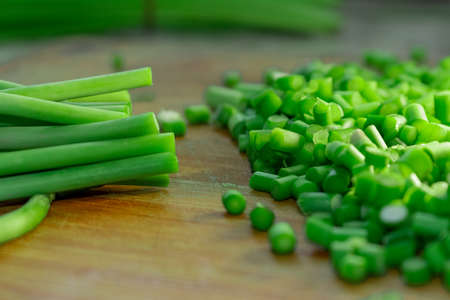 Cutting green garlic on wooden cutting boardの写真素材