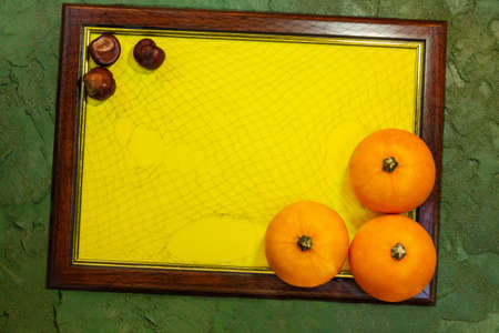 Frame with yellow paper blank space for text with pumpkins and buckeye on the green background. List for recording. Copy spaceの写真素材