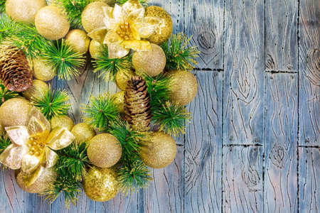 Shiny yellow Christmas balls and cone with barks and pine branches on blue gray wooden background. New year cardの写真素材