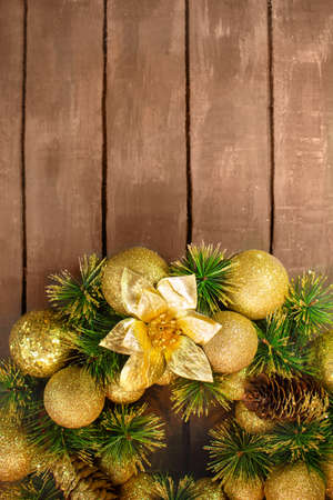 Shiny yellow Christmas balls and cone with barks and pine branches on brown wooden boards background. New year cardの写真素材