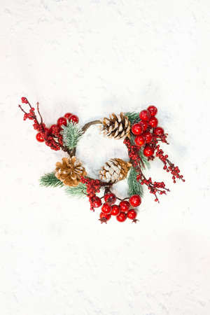 Red berries with fir branches and cones. Christmas wreath on white background with snow. New year card. Copy spaceの写真素材