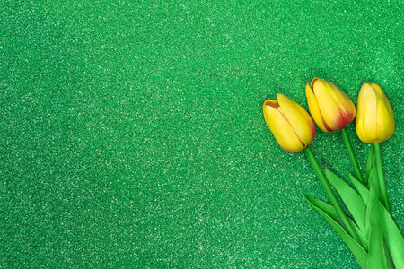 Three yellow tulips on green background with sparkles. Greeting card with Easter, March 8, happy birthday, mother's day. Copy spaceの写真素材