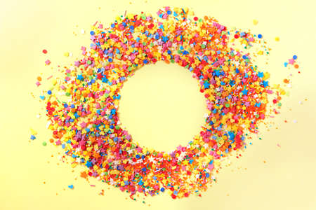 Sweet candy confetti in the middle of a circle with empty space for text. Yellow backgroundの写真素材