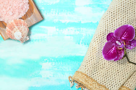 Wooden bowl with pink sea salt with seashell and mesh with purple orchid. Beauty and SPA. Turquoise background. Copy spaceの写真素材