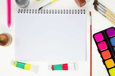 Back to school concept. Painting supplies. Brushes, watercolor and acrylic paints, gouache, markers. In the middle is a notebook, album or sketchbookの写真素材