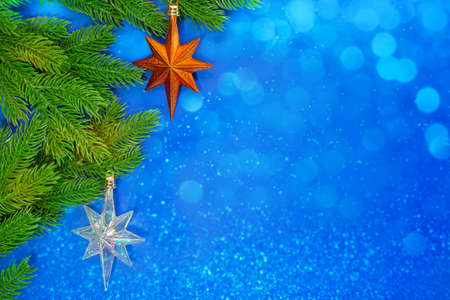 Pine branches with orange star and icy on blue background with bokeh. Christmas, New Year. Copy spaceの写真素材