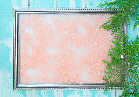 Frame with textured pink background on blue with branch of green thuja. Winter. Christmas, new year. Copy spaceの写真素材