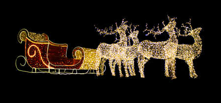 Christmas reindeer from light bulbs with red sleigh of Santa Claus on a black isolated background. Christmas, New Year. Copy spaceの写真素材