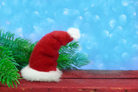Santa Claus hat on a wooden board with fir branches on a blue background with bokeh. Christmas, new year. Copy spaceの写真素材