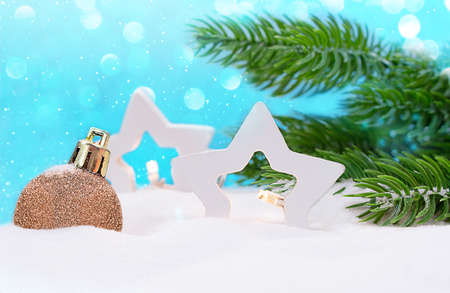 Two white star lanterns and Christmas tree toy on the snow with fir branches. On blue background, snowflakes and bokeh. New year, winter. Copy spaceの写真素材