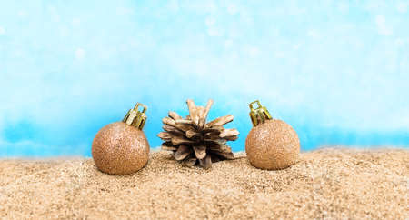 Shiny balls with pine cone on the beach. Concept for Christmas, New Year, Beach Party. Copy spaceの写真素材