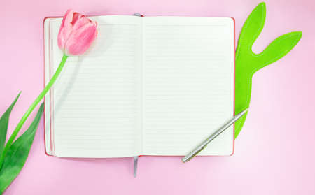 Tulip and green felt hare with notebook and pen on pink background. Easter. copy spaceの写真素材