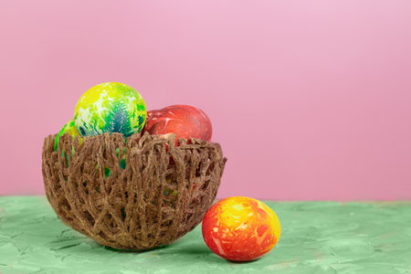 Colored eggs in nest on green and pink background. Easter. copy spaceの写真素材